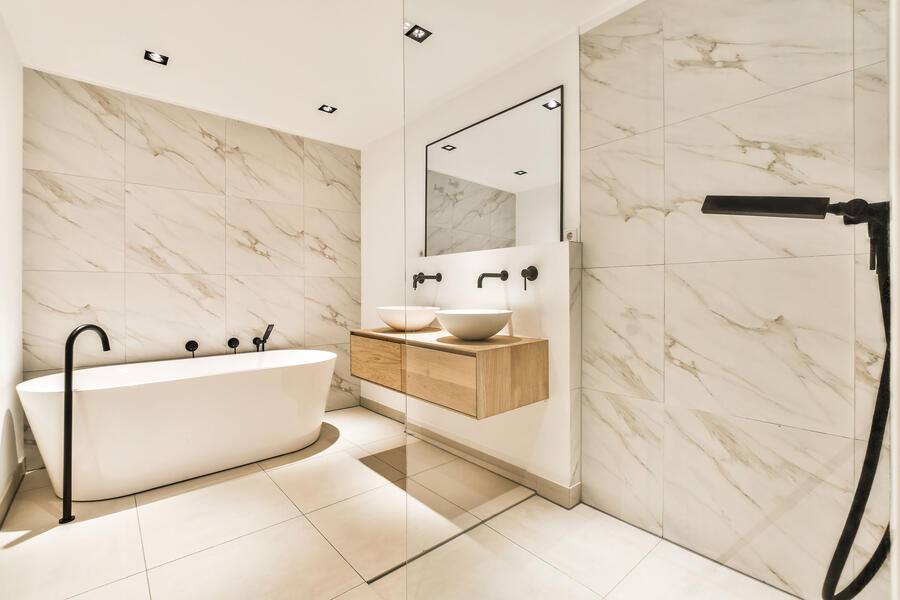 Two workers installing a glass skylight on a roof under construction, with wooden framing and a plastic weather barrier underneath.